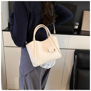 Close-up of off-white lychee leather tote bag with iconic elephant charm accessory