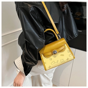 Detail of cartoon bear embossing and silver twist lock on yellow PU leather square bag