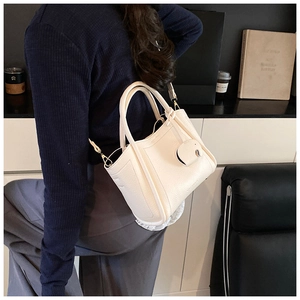 Detail of off-white lychee grain leather bucket bag with gold hardware and elephant charm
