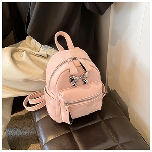 Gros plan d'un mini sac à dos rose avec nœud argenté et finition à texture mate
