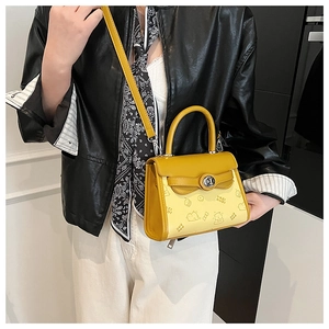 Detail of cartoon animal embossing and silver metal twist lock on the yellow crossbody bag