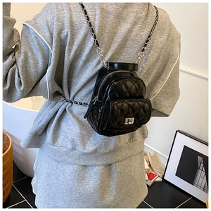Rear view of model wearing a black quilted mini backpack with silver chain straps