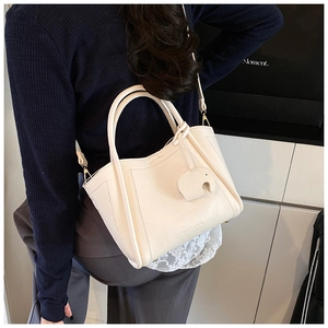 Detail of cream white lychee pattern leather bucket bag with cute elephant charm