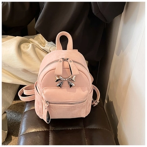 Gros plan d'un mini sac à dos rose avec nœud en métal argenté et texture suédée