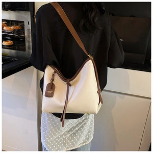 Détail d'un sac hobo en cuir grainé crème et marron avec accessoire étiquette de mode