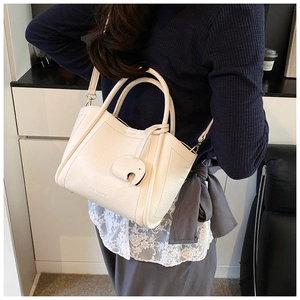 Detail view of cream lychee leather bucket bag featuring a cute elephant charm