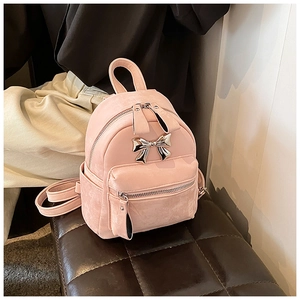 Détail d'un mini sac à dos rose avec nœud métallique argenté et finition en daim