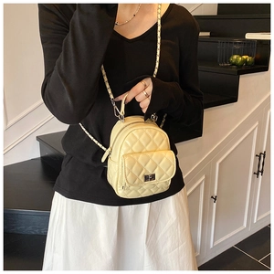 Detail of beige quilted mini backpack featuring chain straps and silver metal turn-lock