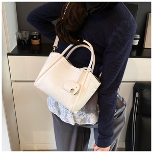 Chic cream white bucket bag with elephant charm shown as a lifestyle crossbody style