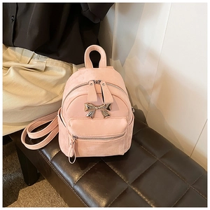 Détail d'un mini sac à dos rose avec nœud doré décoratif sur un banc en cuir