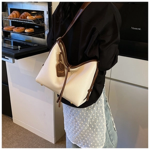 Gros plan d'un sac cabas en cuir beige avec des lanières marron dans un décor chaleureux