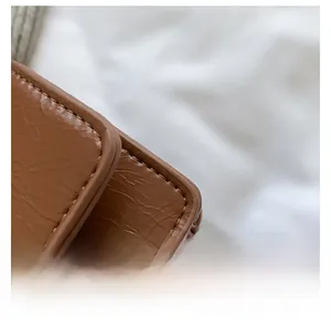 Dettaglio della rifinitura dei bordi e delle cuciture su una mini borsa in pelle marrone