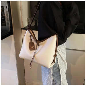 Détail du grand sac cabas en cuir écru avec bordure marron et pieds de protection