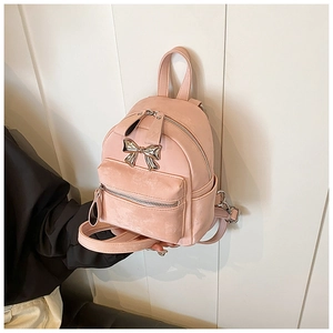 Gros plan du mini sac à dos rose avec nœud argenté et texture en cuir mat