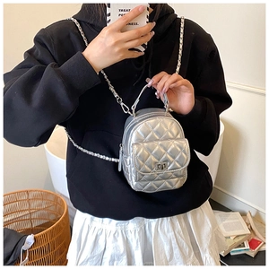 Detail of silver quilted mini backpack bag with metal chain strap and turn-lock closure