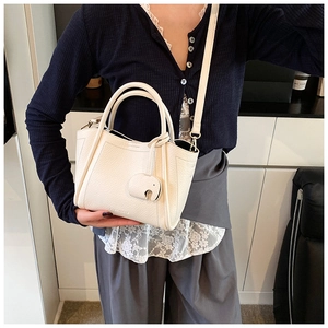 Detail of cream bucket bag with grain leather texture and elephant charm on model
