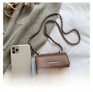 Mini borsa a tracolla marrone con catena accanto a uno smartphone per mostrare la taglia