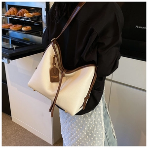 Détail du sac hobo en cuir crème avec cordon marron et étiquette latérale en cuir