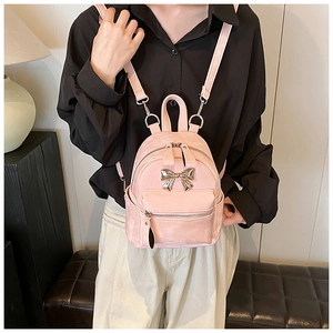 Détail du mini sac à dos rose avec nœud argenté et bandoulière réglable pratique