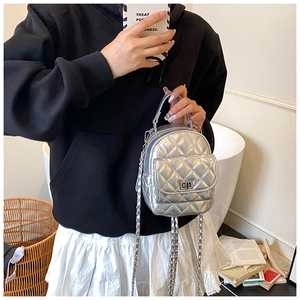 Detail of silver quilted mini backpack featuring shiny leather finish and chain straps