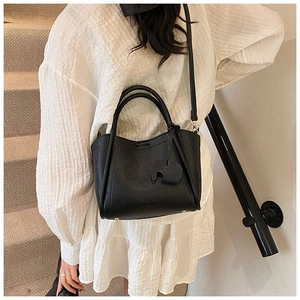 Detail of black pebbled leather bucket bag with cute elephant charm and bottom studs