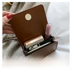 Dettaglio della capacità interna della mini borsa marrone con rossetto e cipria