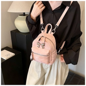 Détail du mini sac à dos rose avec nœud doré et texture en cuir synthétique
