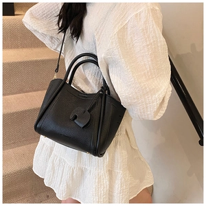Detail of black pebbled leather tote with a unique elephant charm and adjustable strap