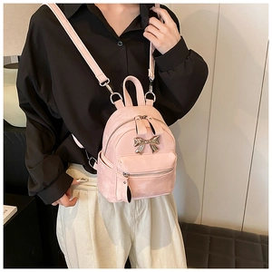 Vue détaillée d'un mini sac à dos rose avec un nœud métallique argenté et des bretelles