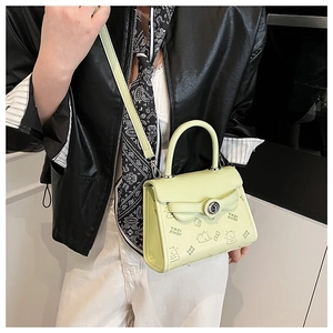 Detail of light green square bag with cartoon prints and silver metallic turn-lock closure