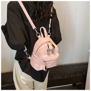 Gros plan du mini sac à dos rose avec nœud doré et bretelles réglables amovibles