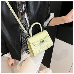 Dettaglio della borsa a mano verde lime con stampe a cartoni animati e chiusura in metallo