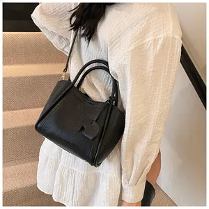 Detail of black pebbled leather bucket bag with cute elephant charm and shoulder strap