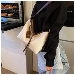 Détail du sac cabas en cuir crème avec bordure marron et clous de protection dorés