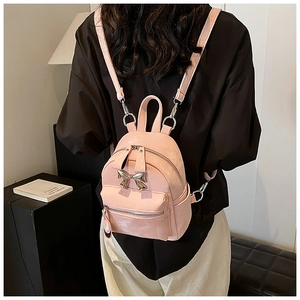 Gros plan d'un mini sac à dos rose avec noeud doré et bretelles métalliques réglables