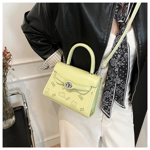 Detail of mint green crossbody bag featuring bear graphics and silver twist lock