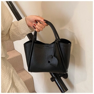 Close-up of black lychee grain bucket bag with handles and cute elephant charm pendant