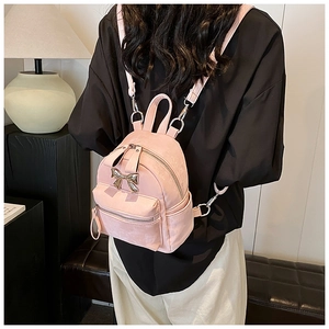 Vue détaillée d'un mini sac à dos rose avec noeud doré porté par un mannequin