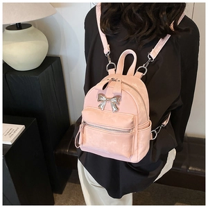 Mini sac à dos rose en cuir avec nœud argenté porté par un mannequin dans un décor chic