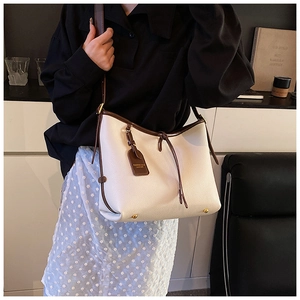 Vue détaillée du sac cabas en cuir litchi blanc avec liseré marron et pieds dorés