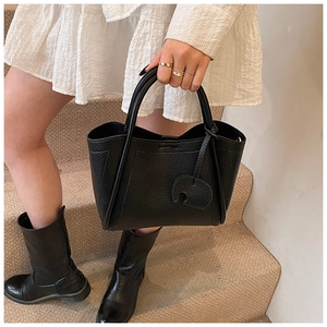 Detail of black litchi leather bucket bag with an elephant-shaped leather charm decoration