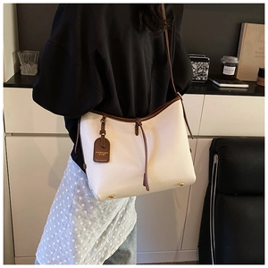 Détail du sac cabas en cuir litchi blanc avec bordure marron et clous de protection dorés