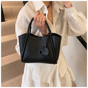 Detail of black pebbled leather bucket bag featuring a unique elephant shaped charm