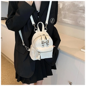 Détail d'un mini sac à dos blanc avec nœud en métal et bandoulières amovibles polyvalentes