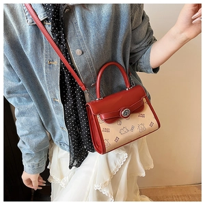 Detail of red and beige shoulder bag featuring cute cartoon patterns and a metal twist lock