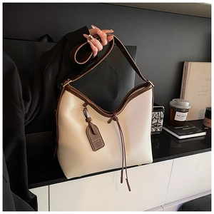 Détail du sac cabas en cuir crème avec poignées marron et étiquette de mode