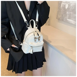 Détail du mini sac à dos blanc avec boucle nœud argentée et fines bretelles