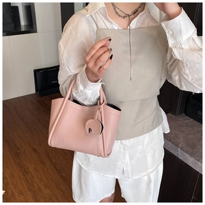 Pink lychee grain leather bucket bag with elephant charm and decorative piping detail