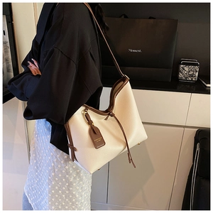 Détail du grand sac cabas beige avec lanières en cuir marron et bordures contrastées