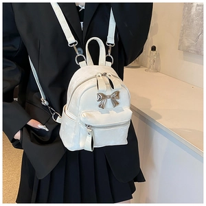 Gros plan du mini sac à dos blanc avec nœud en métal sur un blazer noir
